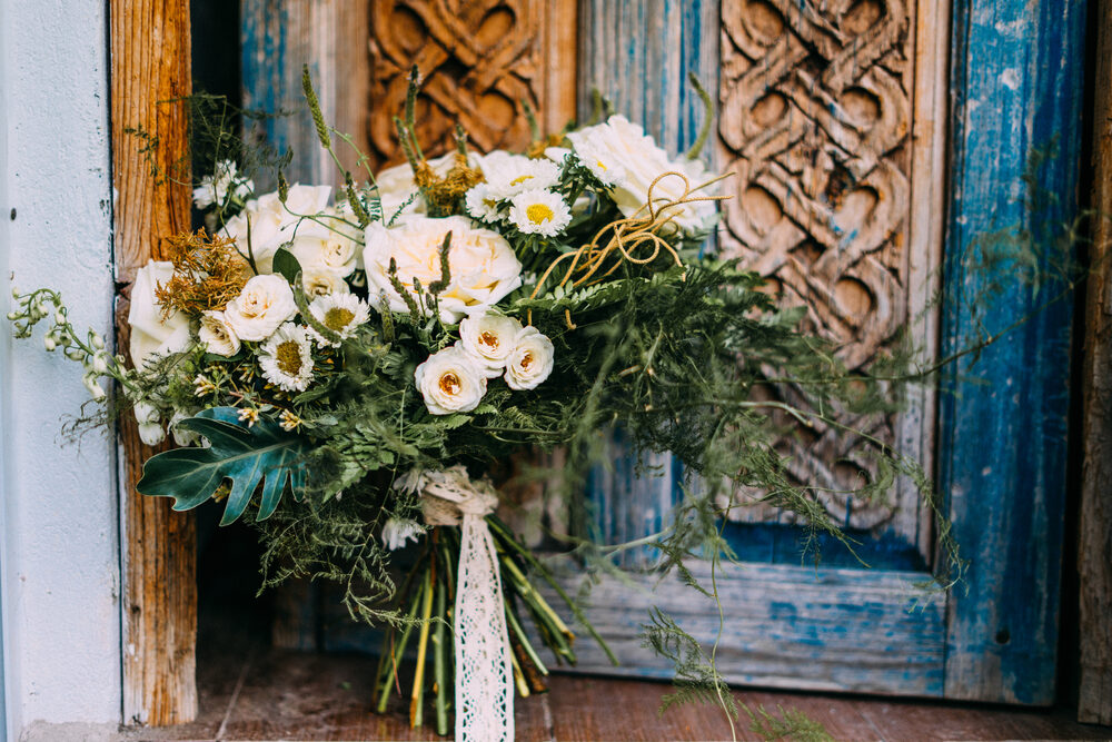 Hand-tied bouquet in front of ornate blue wooden door