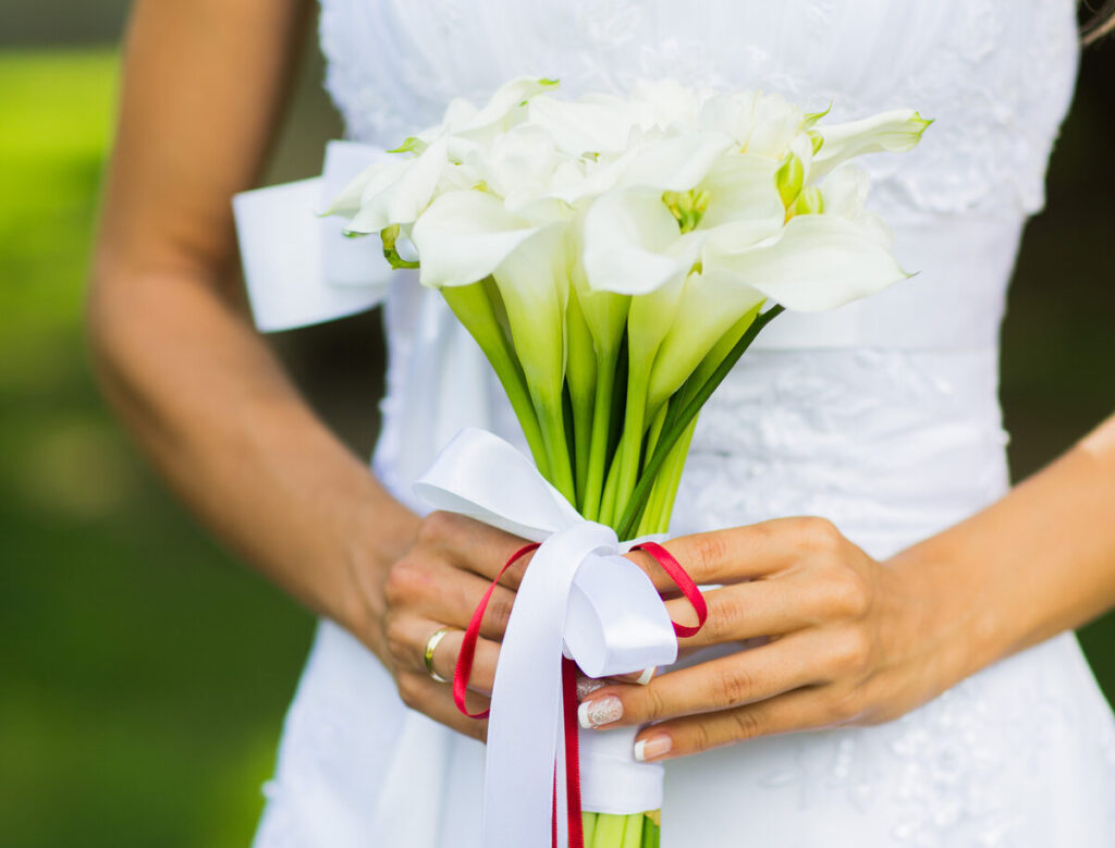 A wand shaped bouquet of calla lillies and white ribbon